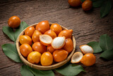 Fresh Achacha fruit or garcinia intermedia in wooden bowl on wooden background, Yellow Madrono Fruit or Lemon drop mangosteen in wooden basket on wooden texture background.