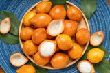 Fresh Achacha fruit or garcinia intermedia in wooden bowl on wooden background, Yellow Madrono Fruit or Lemon drop mangosteen in wooden basket on wooden texture background.