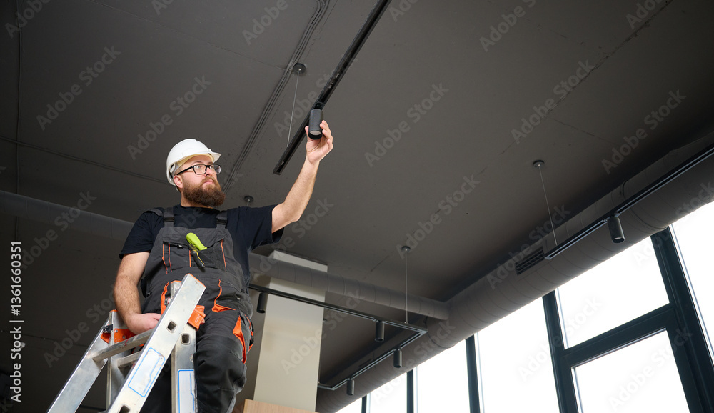 Man install a spot track LED light in the ceiling at the new office ...