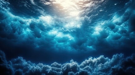 Poster - Underwater scene with sunlit surface above dark blue water and clouds below.