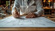 © Zikie_ - Person in a lab coat working on architectural blueprints with a pen