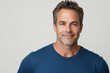 © TENphoto - Confident man with gray hair smiling in casual blue shirt against neutral background