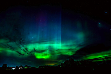 northern lights dancing over country landscape in north of sweden.