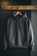© irina - Stylish charcoal hoodie displayed on wooden hanger against dark wall in a contemporary setting for casual fashion enthusiasts