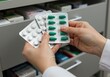 © Hello Stock - A close-up of a pharmacist or healthcare worker hands holding two blister packs of medicine one with white tablets and another with green capsules