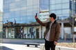 © Austockphoto - Young Chinese university student standing taking a photo with mobile phone