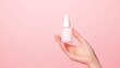 © Phatharaporn - Woman's Hand Holding Skincare Serum Bottle on Pink Background