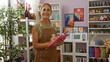 © Krakenimages.com - Woman smiling while taking notes in a home decor shop with plants and artwork around, showcasing a beautiful mature female in an interior setting with shelves and decorative items.
