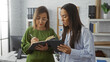 © Krakenimages.com - Women working together at office, focused on tasks with notebook and tablet in a modern indoor workspace