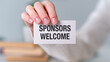 © Pawel - A person holding a white card that says Sponsors Welcome