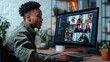 © QuietWord - an African man sitting at office working desk online VDO conference steaming with other co-worker