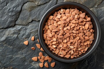 Aufkleber - Bowl filled with light brown seeds resting on a dark stone surface, showcasing natural textures and colors