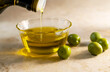 © Tetra Images - Olive oil pouring into small glass bowl with olives on table