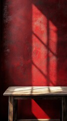 Poster - Warm sunlight filters through a window, creating a play of shadows on a simple wooden table. The backdrop features a striking red wall that adds depth and warmth to the ambiance