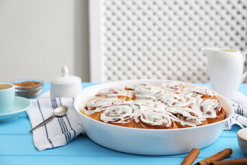 Wall Mural - delicious frosted cinnamon rolls in baking dish on light blue wooden table indoors, closeup