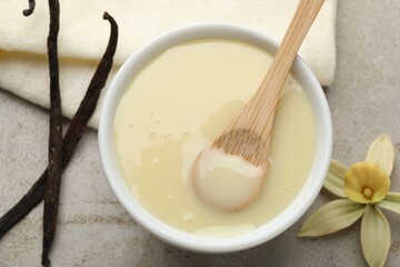 Wall Mural - tasty condensed milk, vanilla pods, flower and spoon on light grey table, flat lay