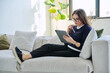 © Valerii Honcharuk - Portrait of middle aged woman using digital tablet sitting on sofa at home