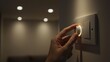 © M - Hand adjusting a light dimmer switch on a wall indoors