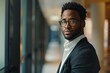 © Baba Images - Portrait of a confident black man in office hallway