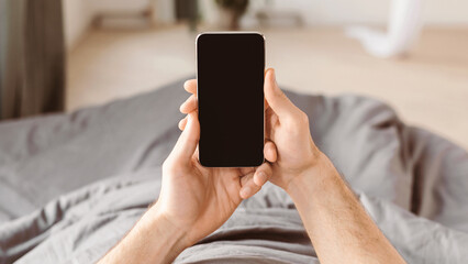 Aufkleber - Unrecognizable Man Using Smartphone With Empty Screen Lying In Bed At Home. Mockup, POV, Panorama