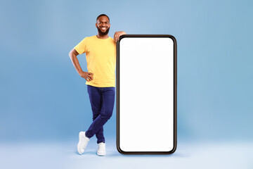 Poster - full length portrait of cheerful african american guy leaning on giant smartphone, demonstrating emp