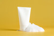 © New Africa - Tube of cosmetic product with foam on yellow background