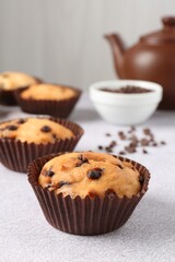 Wall Mural - delicious muffin with chocolate chips on light grey table, closeup