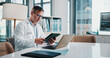 © peopleimages.com - Healthcare, laptop and tablet with doctor man at desk in office of hospital for diagnosis, planning or research. Computer, medical and technology with mature medicine professional reading in clinic