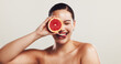 © KayExam/peopleimages.com - Happy woman, beauty or skincare with grapefruit for detox or vitamin C on a white studio background. Female person, model or smile with tongue out for natural organic fruit, healthy skin or nutrition
