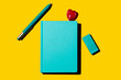 © VISTA by Westend61 - Turquoise notebook with pen, eraser, and heart-shaped lollipop on yellow background