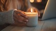 © Daphne - Caucasian female hand holding lit candle near laptop on cozy evening