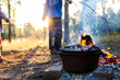 © Austockphoto - Camp oven over campfire cooking dinner - kids play nearby fire