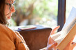 © Austockphoto - Teen girl reading a novel in the lounge room by a window in winter