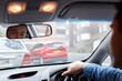 © Austockphoto - Asian man looking in rear view mirror whilst driving in car