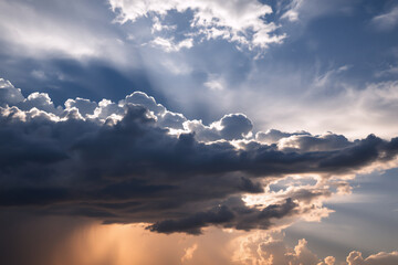 Aufkleber - Dramatic sky with dark storm clouds contrasted by bright sun rays breaking through, illuminating the blue sky above.