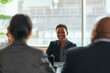 © Maskot - Smiling short haired female business professional at meeting with colleagues in office board room