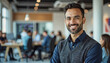 © f_bossa - A portrait headshot photo of a friendly professional CEO executive business worker: A smiling man with a beard stands confidently in a modern office space, looking directly at the camera.