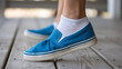 © hobonski - A woman slips into a blue canvas shoe, heel flexing, on a porch with a gentle breeze.