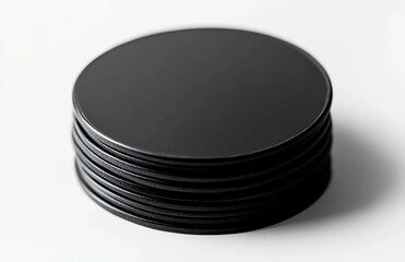 Poster - A close up of a stack of black circular discs on a white surface in a studio setting with soft light