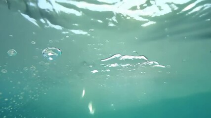 Poster - A clear blue ocean with bubbles floating in it. The bubbles are small and scattered throughout the water