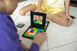 © evgeniia_1010 - Two individuals are sitting on a soft rug indoors, focused on a puzzle game that uses bright, vibrant colored blocks. They appear engaged and enjoying the challenge of the game