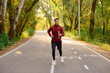 © Bliss - Stylish young man jogging through a vibrant autumn park pathway, embracing fitness and fashion