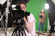 © New Africa - Happy camerawoman with camera in modern film studio, selective focus