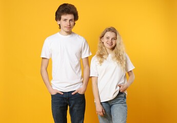 Wall Mural - young woman and man wearing blank white t-shirts on orange background. mockup for design