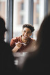 © VGX Ultra - Joyful Young Man Sharing Laughter Over Coffee in Bright Café with Natural Light