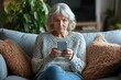© lan - Unhappy older woman sitting on couch, holding smartphone feels frustrated and concerned, received upsetting news in sms, experiencing personal or family problems, misunderstanding through messages