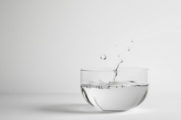 Wall Mural - Water droplets splashing into a glass of water, creating ripples and bubbles.