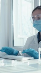 Aufkleber - In a welllit laboratory, a dedicated scientist wearing a lab coat and protective gear diligently types on a keyboard, fully engaged in important research and extensive analysis related to vaccines