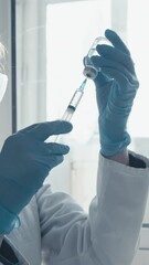 Aufkleber - A focused scientist in a white lab coat and blue gloves prepares a vaccine by extracting liquid from a vial in a sunlit lab, highlighting the importance of essential medical research