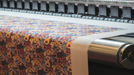 Poster - A machine is printing a colorful piece of fabric with a pattern of animals. The machine is in a factory setting